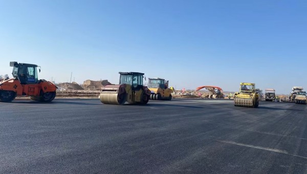 近日，在西部市政建設(shè)集團(tuán)蘭州新區(qū)城市礦產(chǎn)與表面處理產(chǎn)業(yè)園區(qū)（二期）周邊基礎(chǔ)設(shè)施項(xiàng)目—園區(qū)西路南延段（緯五十路至緯二十八路）項(xiàng)目現(xiàn)場(chǎng)，隨著一輛輛運(yùn)料車平穩(wěn)駛?cè)?，攤鋪機(jī)將滾燙的瀝青混合料均勻鋪開(kāi)，標(biāo)志著項(xiàng)
